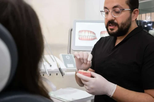 bearded dentist with glasses explaining teeth treatment plan patient during appointment