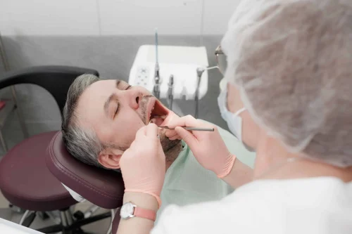 A female dentist treats the teeth of a male patient in a modern office of a dental clinic. Concept of medicine, dentistry and healthcare. Dental equipment